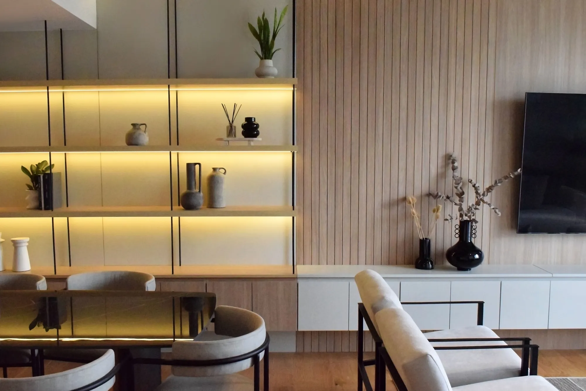Biblioteca con estantes iluminados y revestimiento de listones de madera