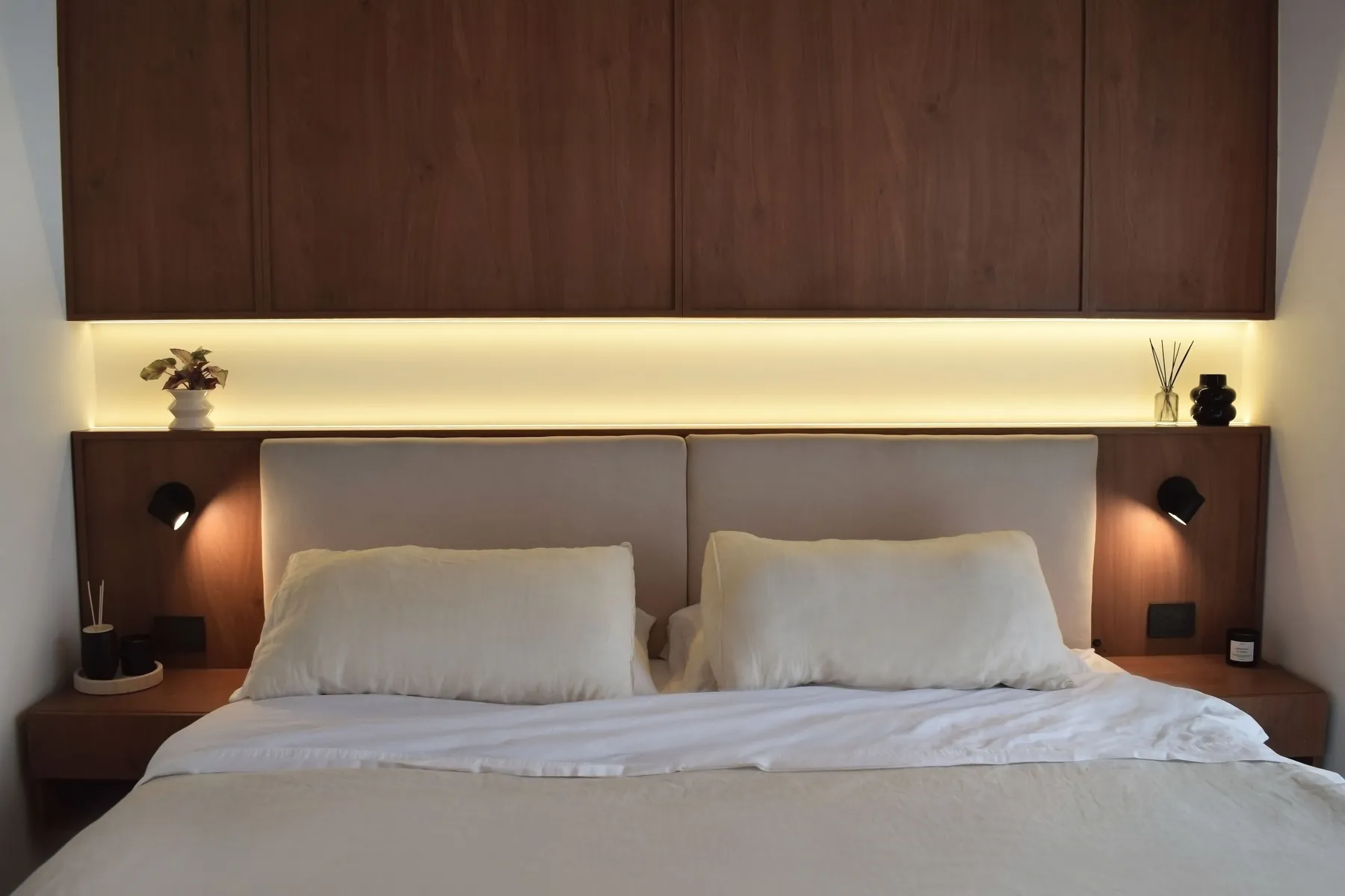 La suite terminada: guardado de madera sobre la cama, luz cálida integrada y respaldo tapizado